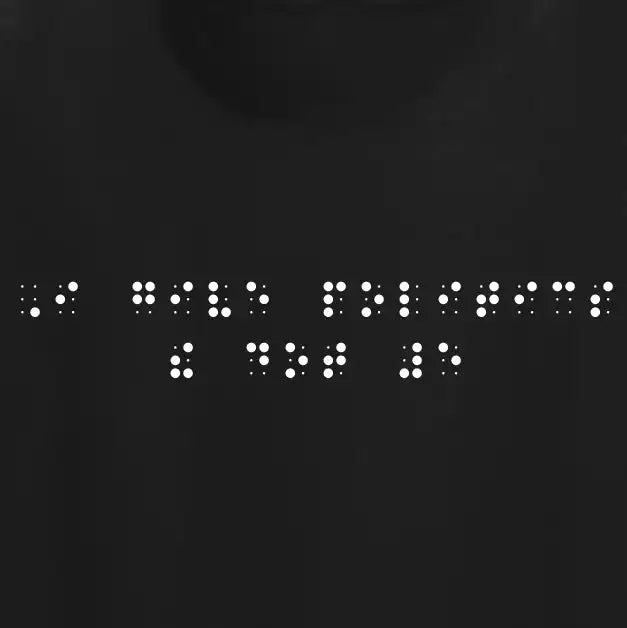 "I give politics the dot 5" printed in white Grade 2 braille across the chest of a black t-shirt.
